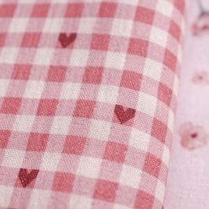 May include: Pink and white gingham fabric with small red hearts printed on it.