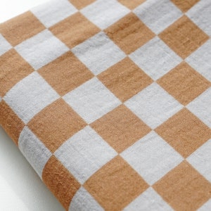 May include: A brown and white checkered fabric with a soft, textured surface.