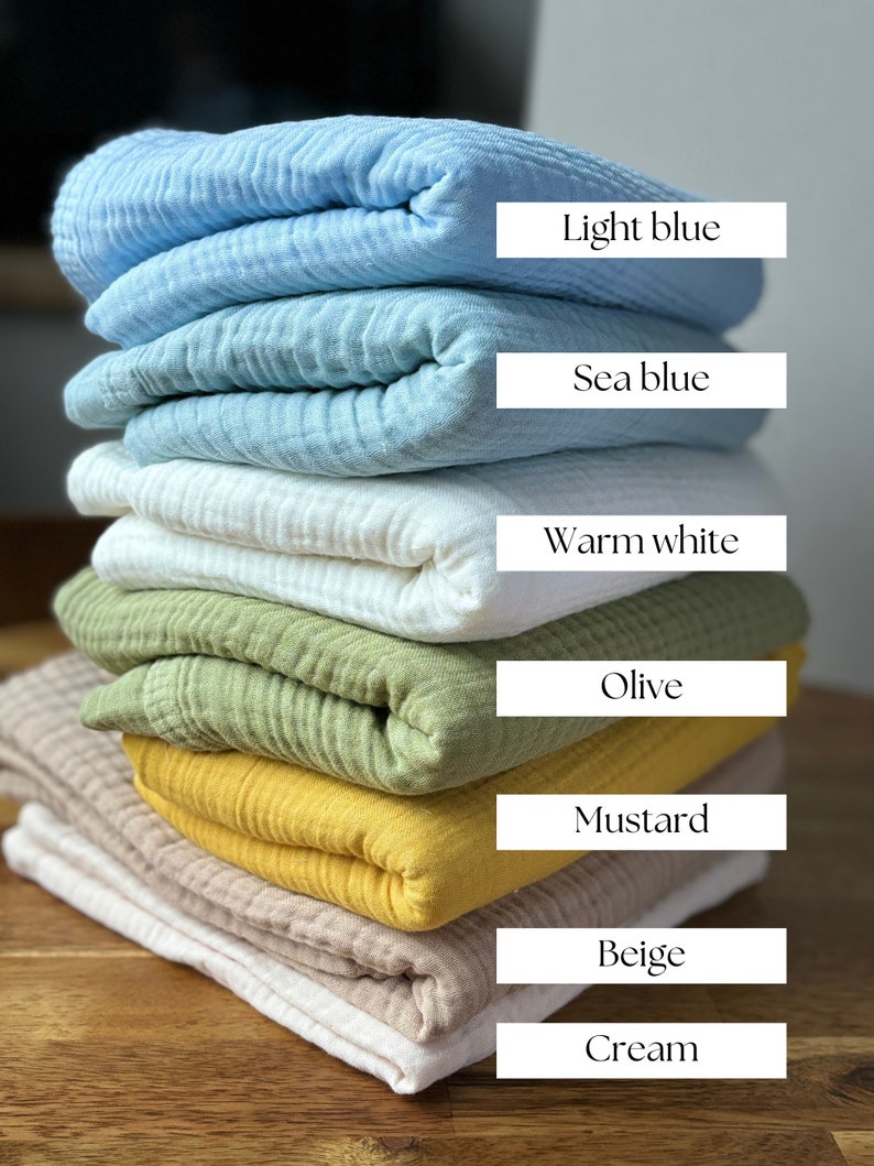 May include: A stack of seven folded fabric swatches in various colors, including light blue, sea blue, warm white, olive, mustard, beige, and cream. The swatches are arranged from lightest to darkest.
