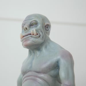 Könnte beinhalten: Nahaufnahme einer grauen, geformten Figur mit einer großen, flachen Nase und einem breiten Mund. Die Figur hat einen großen, fleischigen Körper und ein kleines, spitzes Ohr.