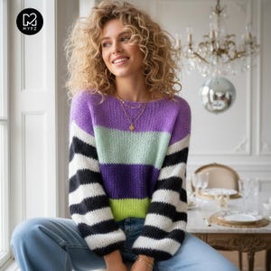 Puede incluir: Un suéter de punto de manga larga con rayas horizontales en tonos morado, verde claro y rayas blancas y negras en las mangas. El suéter tiene un cuello redondo y un ajuste relajado, confeccionado con una textura de hilo grueso.