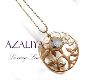 May include: Gold-toned pendant necklace with a tree-of-life design and a central, faceted, gray gemstone. The pendant hangs from a delicate ball chain. The word "AZALIYA" and "Luxury Line" are printed in the image.