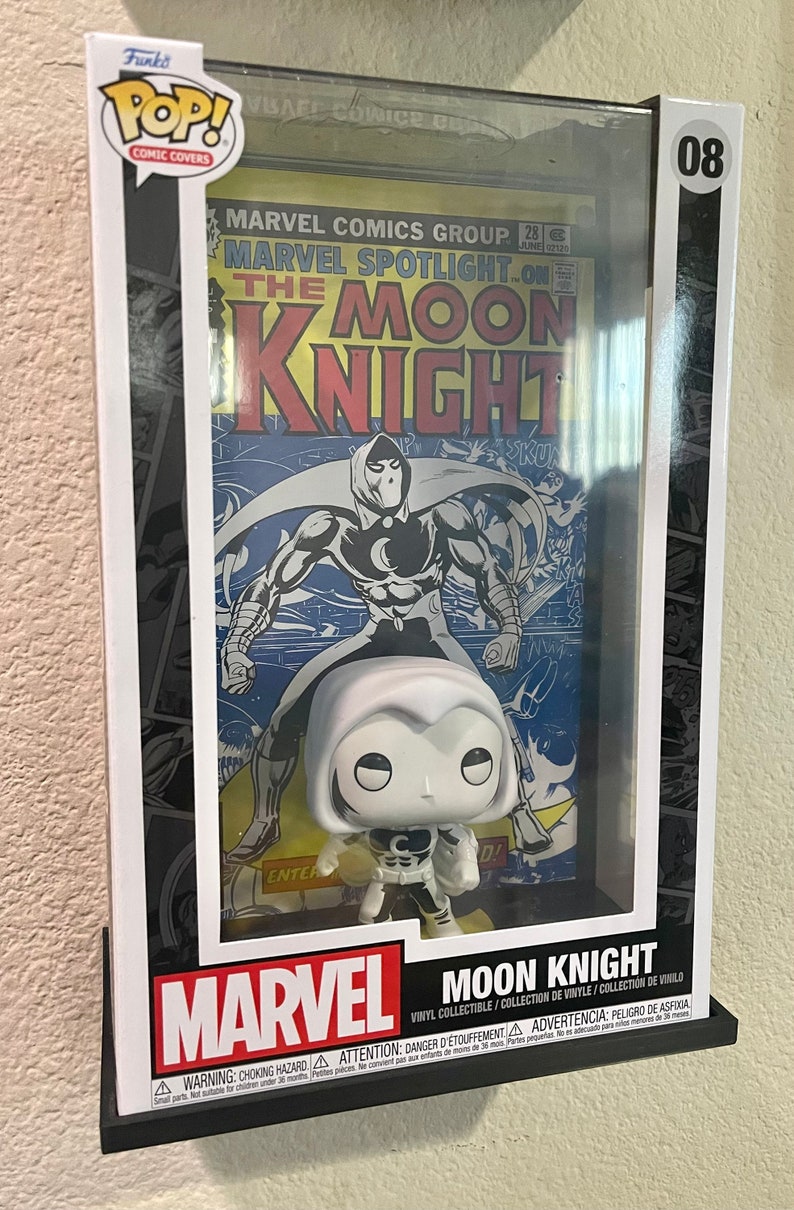 May include: A Funko Pop! Comic Covers vinyl collectible figure of Moon Knight in a black and white costume. The figure is displayed in a clear plastic case with a vintage Marvel Spotlight comic book featuring Moon Knight on the cover. The comic book cover is yellowed and has a red title.