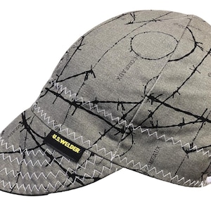 May include: Gray welding cap with a black barbed wire pattern and a yellow "U.S. WELDER" label.