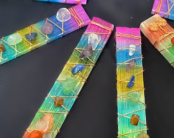 May include: A set of seven rainbow colored crystal wands with copper wire wrapped around them. Each wand has a different colored crystal at each end, representing the seven chakras.