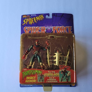 Peut inclure: Une figurine d'action Spider-Man avec une armure d'insecte transformable. La figurine est rouge et bleue avec des toiles d'araign&eacute;e noires et tient une &eacute;p&eacute;e. L'emballage pr&eacute;sente le texte "Spider-Man Spider Force" et "You Turn Spider-Man Into A Powerful CyberSpider!"