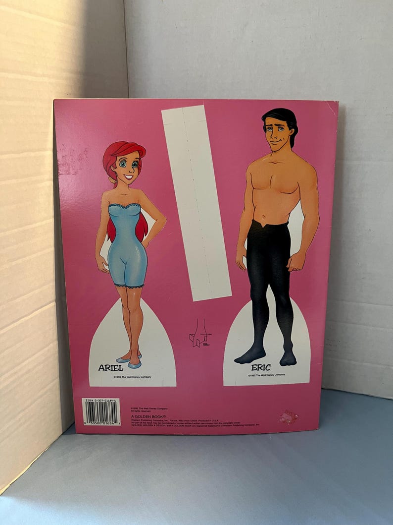 May include: A paper doll set featuring Ariel and Eric from the Disney movie The Little Mermaid. The dolls are printed on a pink background and have cut-out lines for easy assembly.