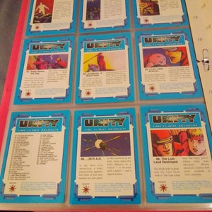 May include: A collection of trading cards featuring illustrations of characters and scenes from a comic book series called "Unity: Time is Not Absolute". The cards are blue and white with a starburst design. The text on the cards includes the title of the series, the card number, and a brief description of the scene depicted.