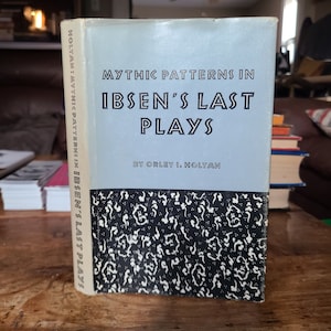 May include: A blue book with the title "Mythic Patterns in Ibsen's Last Plays" by Orley I. Holtan. The book cover features a black and white patterned design.
