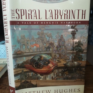 May include: The Spiral Labyrinth: A Tale of Henghis Hapthorn by Matthew Hughes. The book cover features a futuristic city scene with a flying vehicle and a quote from Paul Di Filippo.