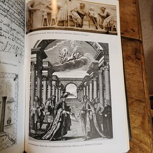Puede incluir: Un grabado en blanco y negro de un grupo de hombres con atuendos formales de pie en un sal&oacute;n con columnas. Los hombres sostienen rollos y parecen estar participando en una ceremonia. El grabado es de las Constituciones de los Francmasones, 1723.