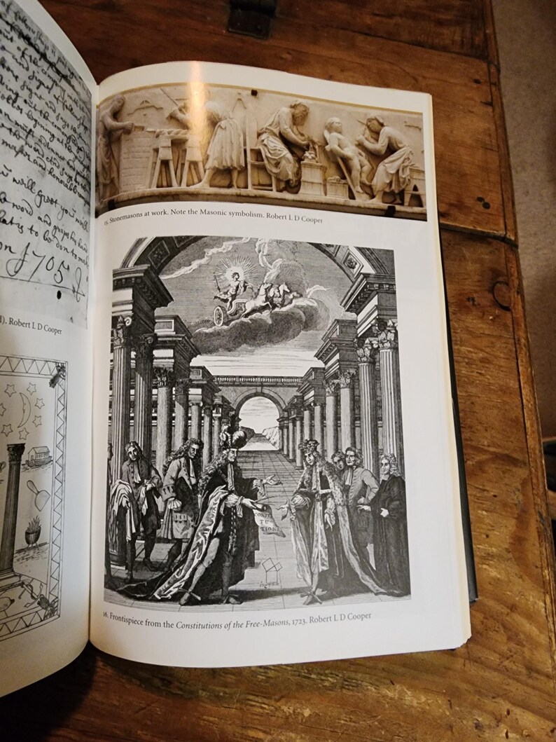Puede incluir: Un grabado en blanco y negro de un grupo de hombres con atuendos formales de pie en un sal&oacute;n con columnas. Los hombres sostienen rollos y parecen estar participando en una ceremonia. El grabado es de las Constituciones de los Francmasones, 1723.