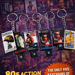 May include: A collection of 80s action movie VHS keychains. Each keychain features a miniature VHS tape design with movie titles like "Die Hard" and "The Terminator". The keychains are attached to silver keyrings, perfect for fans of retro cinema.
