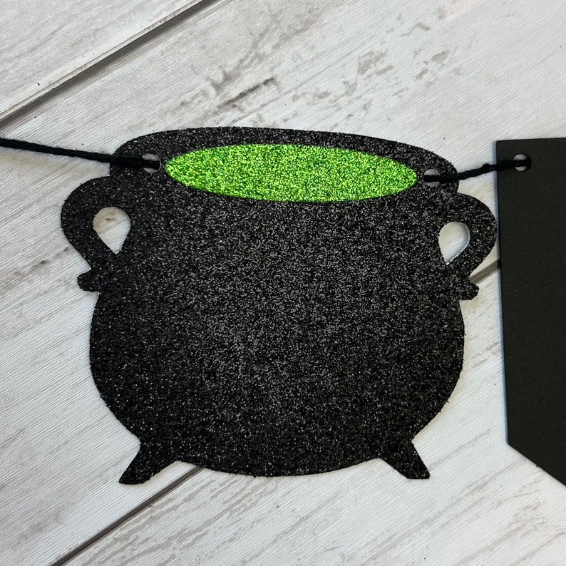 Puede incluir: Caldero negro con purpurina verde en su interior, parte de una pancarta de Halloween.