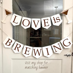 May include: White banner with brown lettering that reads "LOVE is BREWING". The banner is decorated with martini glass cutouts. The text "visit my shop for matching banner" is below the banner.