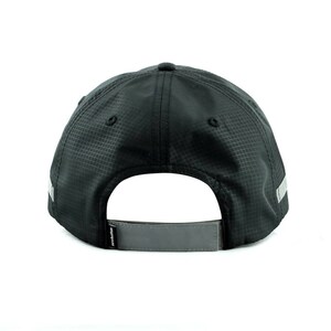 May include: Black baseball cap with a reflective gray stripe around the brim and a reflective gray strap in the back. The cap has a textured, woven fabric.
