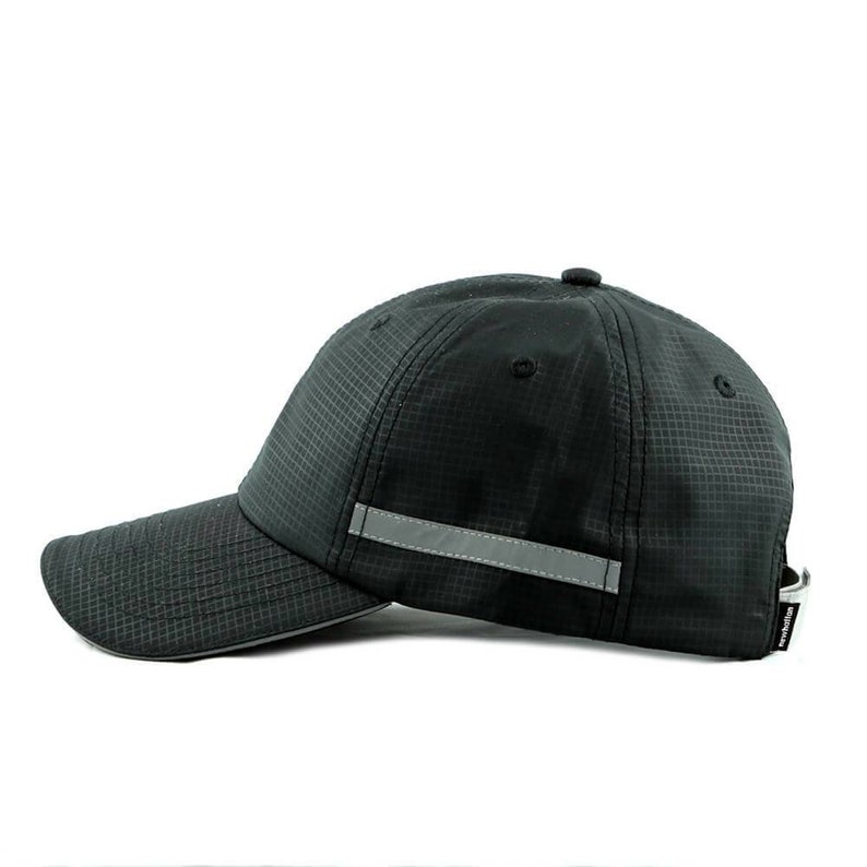 May include: A black baseball cap with a reflective strip on the front. The cap has a structured crown and a curved brim.