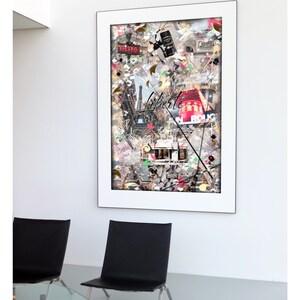 May include: A framed collage of images depicting Paris, France. The collage includes the Eiffel Tower, a red bus, a street sign that says "Liberte", and a vintage Parisian cafe. The collage is in a white frame and is hanging on a white wall.
