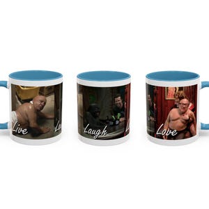 May include: White ceramic mug with a blue interior and handle. The mug features three different images with the words "Live, Laugh, Love" printed on the front. The images are of three different people in humorous poses.
