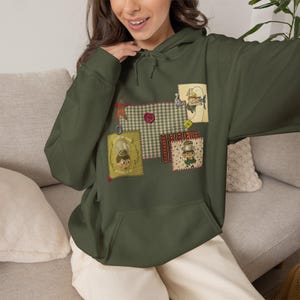 Pode incluir: Uma camisola com capuz verde-azeitona com um bolso frontal grande e uma colagem de remendos retangulares. Os remendos exibem vários padrões, incluindo xadrez verde, e ilustrações de personagens de desenhos animados com pequenos botões.