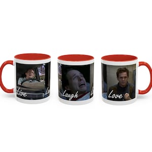 May include: Set of three white ceramic mugs with red interiors and handles. Each mug features a different image of a man with the words "Live", "Laugh", and "Love" in a handwritten font. The mugs are designed for hot beverages.