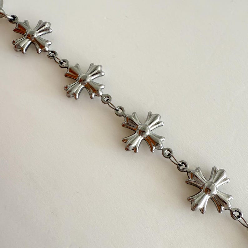 May include: A silver chain bracelet with multiple silver cross charms.