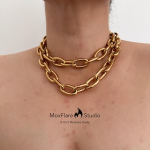 Könnte beinhalten: Eine goldfarbene Halskette mit zwei Reihen großer, ovaler Glieder. Die Halskette wird um den Hals getragen. Das Bild enthält den Text "MoxFlare Studio" und das Copyright-Jahr.