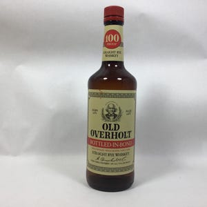 May include: A brown glass bottle of Old Overholt Straight Rye Whiskey, bottled-in-bond. The label features the text "100 Proof" and a portrait of a man. The bottle has a red cap and a cream-colored label.