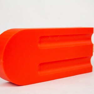 May include: A vibrant, oversized orange popsicle with three grooves and a wooden stick. The bright color and playful design suggest a fun, summery theme. The product is a decorative item.