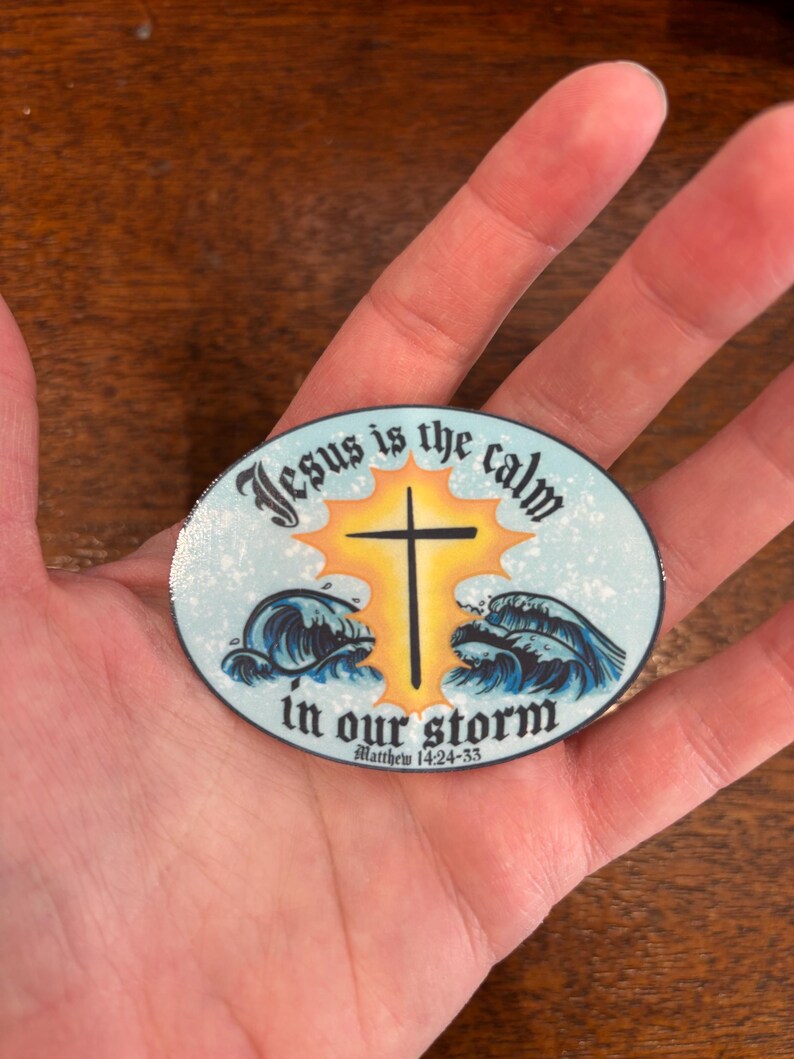 May include: A round sticker with a blue, white, and yellow design. The sticker features a cross with a sun behind it and waves in front of it. The text on the sticker reads "Jesus is the calm in our storm" and "Matthew 14:24-33".