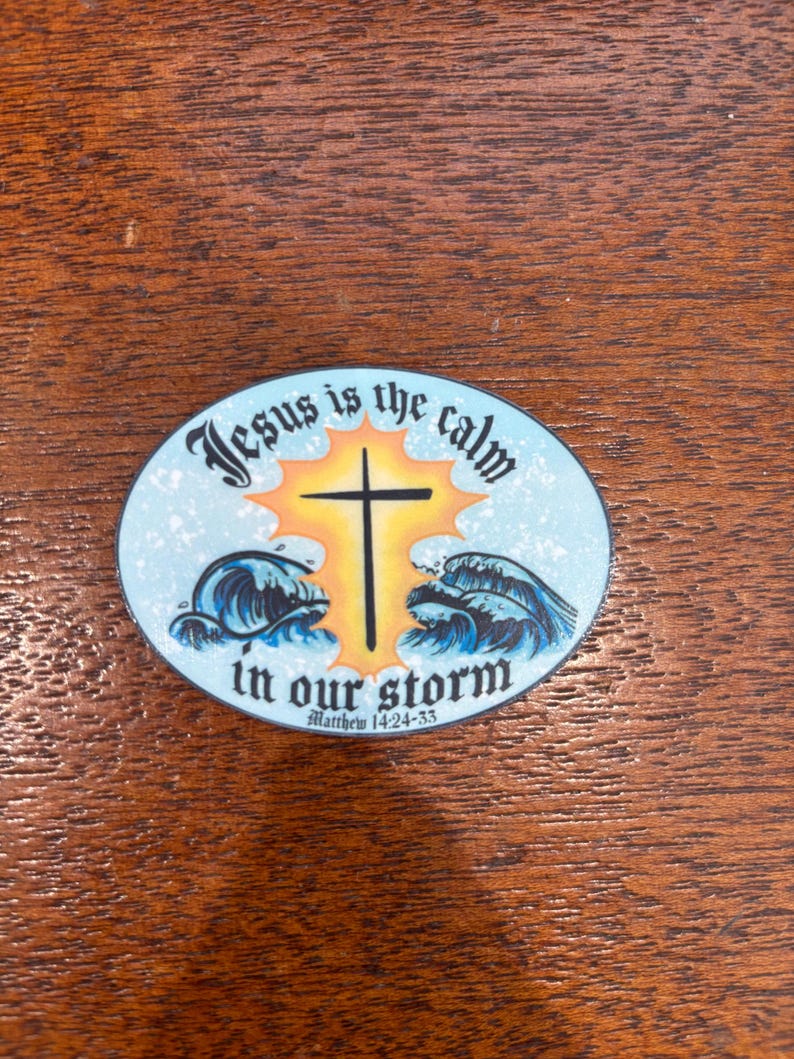 May include: A blue and white round sticker with a yellow sunburst behind a black cross. The sticker says "Jesus is the calm in our storm" with the scripture reference "Matthew 14:24-33" underneath.