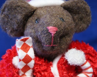 May include: A plush brown bear wearing a Santa Claus outfit. The bear has a white hat, a pink nose, and a red and white candy cane. The outfit is red with white trim. The bear is a festive holiday decoration.