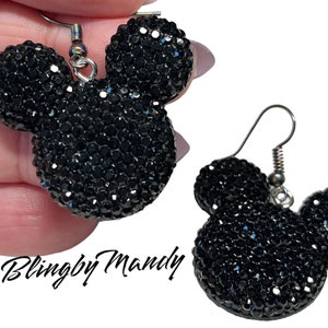 May include: Black rhinestone Mickey Mouse earrings with silver hooks. The earrings are made of black rhinestones that are set in a Mickey Mouse shape. The earrings are approximately 2.5 cm in diameter.