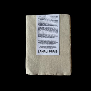 May include: An off-white rectangular paper product with a white label bearing French text and the brand name "LAMALI PARIS." The item is presented against a black backdrop, emphasizing its texture and design.