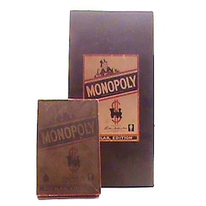 Puede incluir: Un juego de mesa Monopoly vintage. La caja presenta el logotipo de Monopoly en un diseño rojo y blanco. La caja más pequeña está delante de la caja más grande. El juego es una edición especial.
