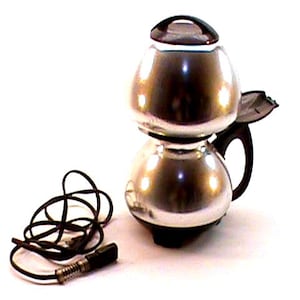 May include: A retro silver coffee maker with a black handle and a glass lid. The coffee maker has a bulbous shape and a black power cord with a plug. The design is likely from the mid-20th century.