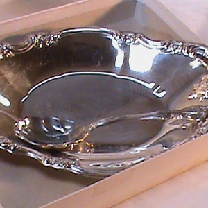 May include: A silver serving dish with an ornate, scalloped edge. The dish is in a white box.