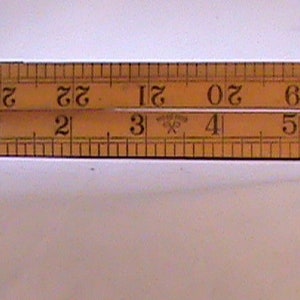 May include: A wooden folding ruler with brass ends, marked with inches and fractions of an inch. The ruler is marked with numbers from 16 to 33.