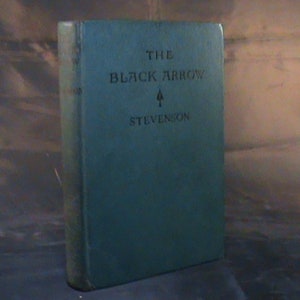May include: A teal blue hardback book with the title "The Black Arrow" and the author "Stevenson" printed on the front cover.