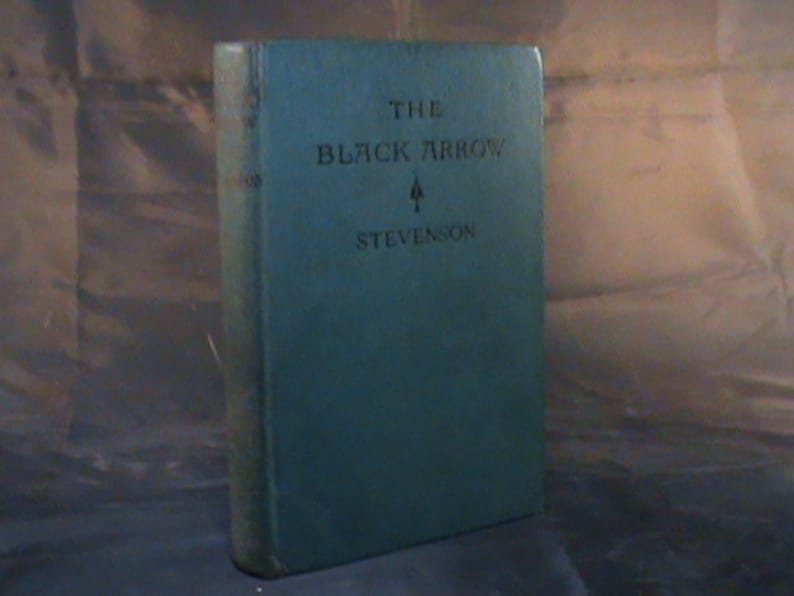 May include: A teal blue hardback book with the title "The Black Arrow" and the author "Stevenson" printed on the front cover.