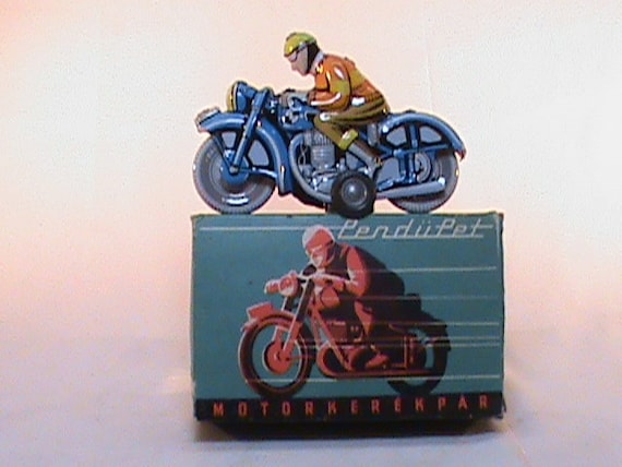 vintage 1960s tin toy with a wind-up mechanism. It depicts a