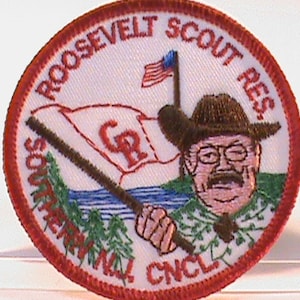 Puede incluir: Un parche bordado en rojo, blanco y azul con el texto "Roosevelt Scout Res. Sorento, CNCL" y una imagen de dibujos animados de un hombre con bigote y gafas sosteniendo un palo.