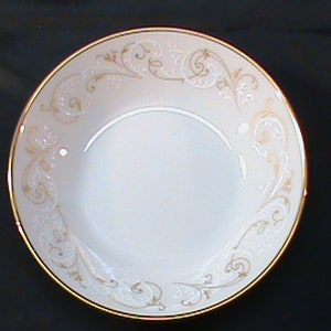 May include: A white ceramic bowl with a gold rim and a delicate floral pattern. The bowl is empty and ready to be used.