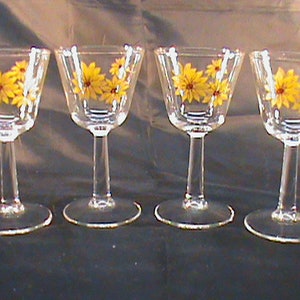 Puede incluir: Juego de cuatro vasos de vidrio transparente con tallo y diseños de flores amarillas.