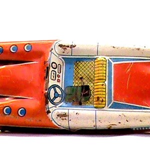Pode incluir: Carro de brinquedo vintage em laranja, branco e azul. O carro retrô apresenta um interior detalhado com volante e assentos. O brinquedo tem um design clássico com sinais de desgaste, sugerindo que é uma antiguidade colecionável.
