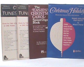 May include: A collection of music books, including "Christmas Holiday" and "The Easiest Christmas Carol Spinet Orga Book." The books are in various colors and sizes, suitable for piano and organ.