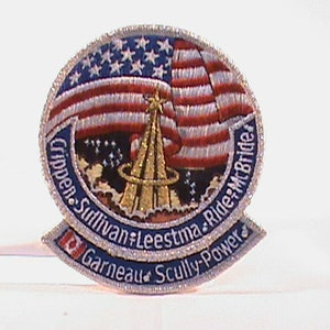 May include: A blue and white embroidered patch with a red, white, and blue American flag. The patch features the names of the astronauts who flew on the Space Shuttle Challenger mission: "Crippen, Sullivan, Leeestma, Ride, Mcbride, Garneau, Scully-Power".
