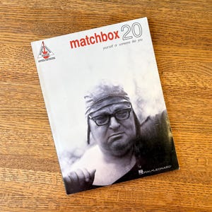 May include: A book cover for "Matchbox 20" featuring a black and white image of a man wearing glasses and a hat. The title is in red, with the text "yourself or someone like you" below it. The Hal Leonard logo is visible.