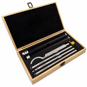 Peut inclure: Une boîte en bois avec un intérieur en mousse noire, contenant un ensemble de six outils en métal. Les outils sont étiquetés "HOLZWERK" et sont disposés dans la boîte. La boîte a un loquet en laiton.