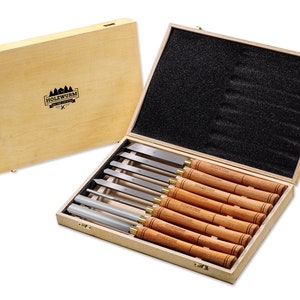 Op de afbeelding: Een set van 10 houtsnijgereedschappen in een houten kist. De gereedschappen hebben houten handvatten en metalen bladen. De kist is gemaakt van licht hout en heeft een zwarte schuimvoering.